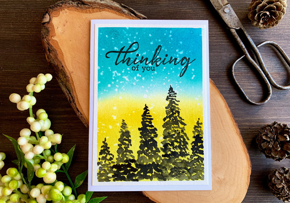 Handmade card with a blue and yellow background and silhouette of trees to support people in Ukraine.