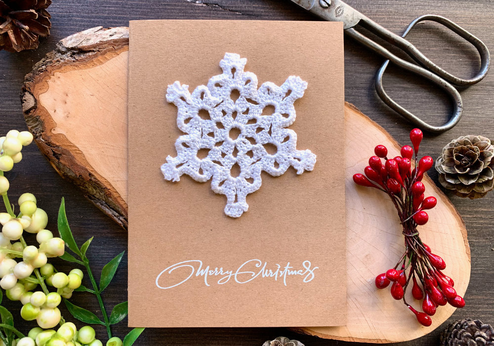 Handmade Christmas card with a white crochet snowflake and Merry Christmas sentiment.