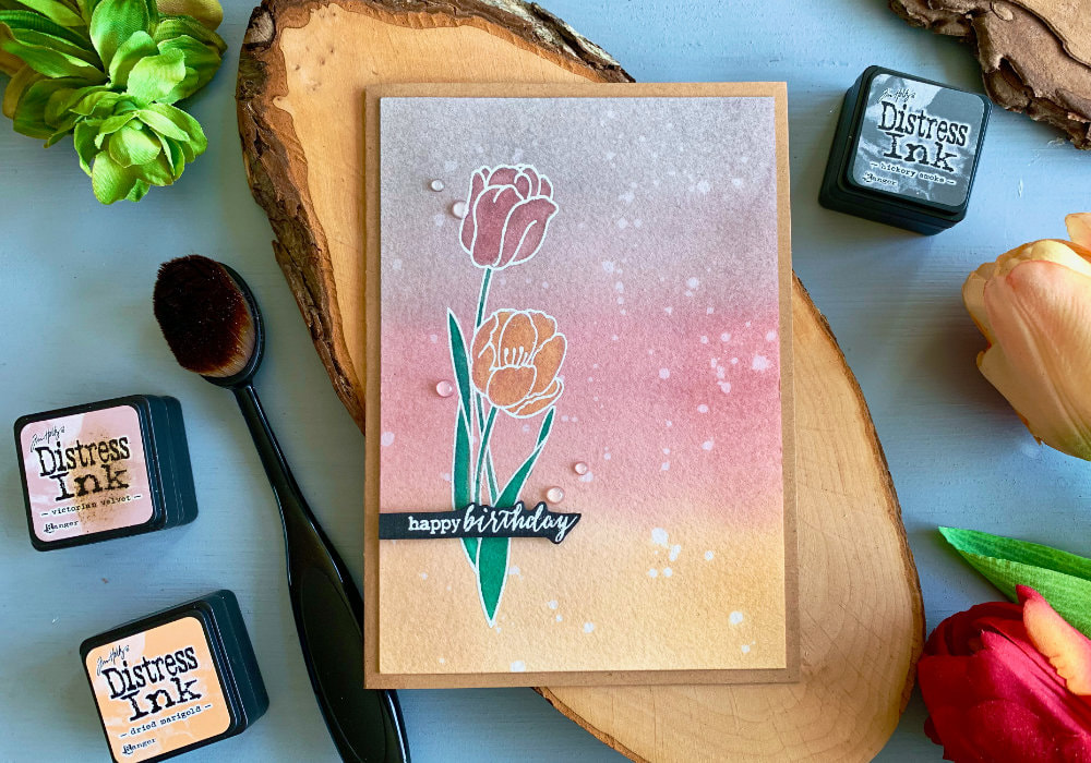 Handmade Birthday card with a background created with Distress inks in colours grey, pink and yellow and a stamped tulips heat embossed in white and watercoloured using the Distress inks - green, pink and yellow. 