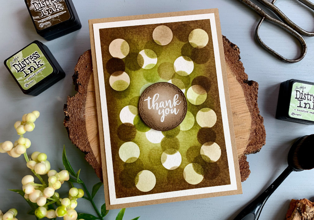 Thank you card with a bokeh effect over a brown-green background made with Distress inks. 
