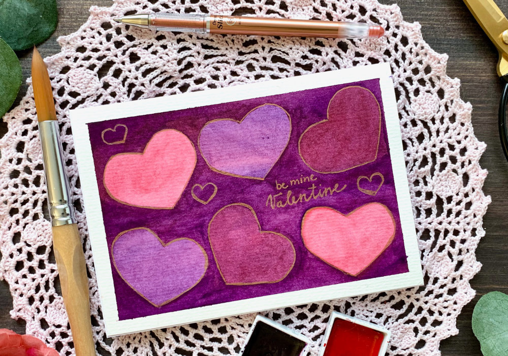 Making a handmade Valentine's Day card completely from scratch, using watercolours and painting a layered negative space background with hearts. Perfect for beginners.