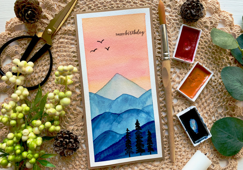 Learn how to paint a simple landscape with mountains at sunset using watercolour and make a beautiful handmade card. Easy landscape sunset mountains watercolour painting for beginners.