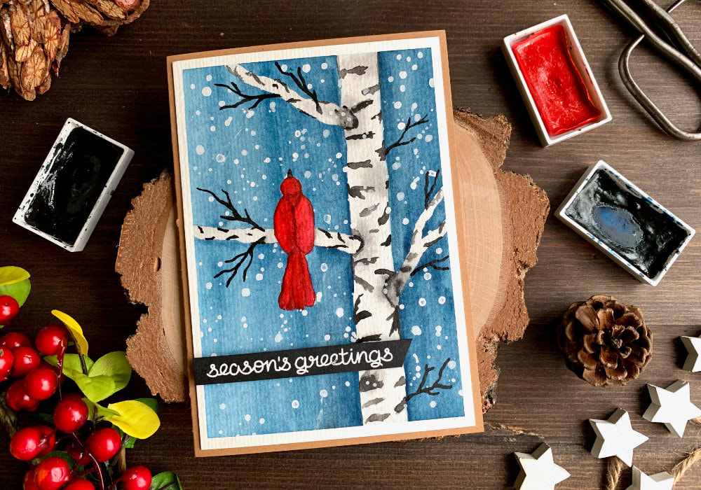 Learn how to draw and paint a simple winter scene with a red bird and birch tree using watercolours and make a DIY Christmas card.

