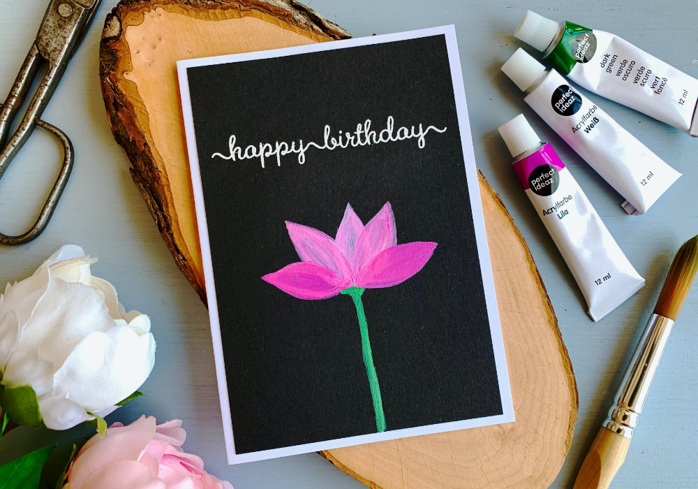 Simple Birthday card with a painted lotus flower using acrylic paints on a black card stock and a greeting heat embossed in white saying Happy Birthday. 