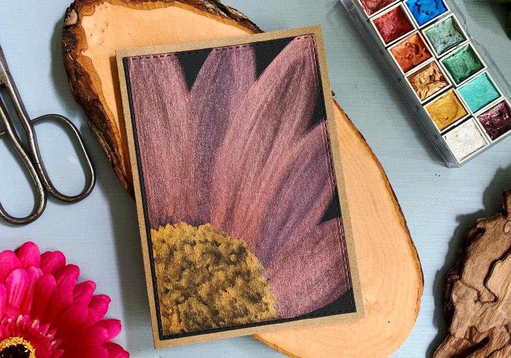 Handmade greeting card with a partial big bold daisy flower painted with pink and gold metallic watercolours on a black card stock.