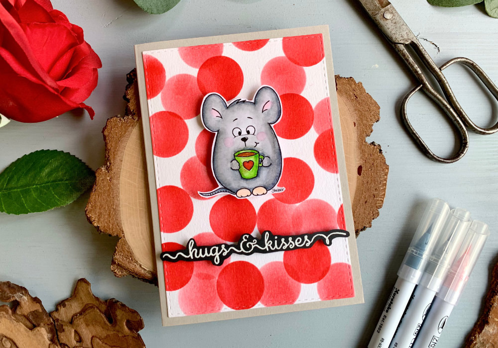 Handmade Valentine's day with a printed digital stamp of a mouse holding a cup of coffee. Coloured in grey with the Zig brush markers and adhered on a very vibrant background filled with red circles and greeting that say hugs & kisses.