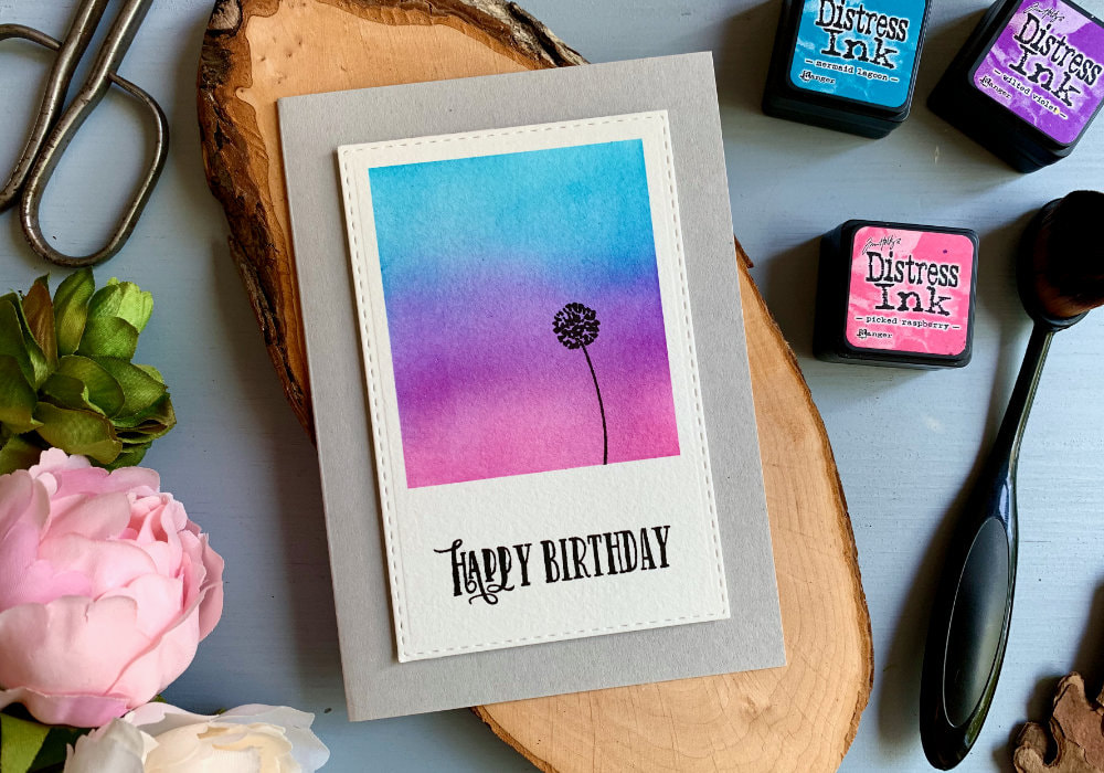 Quick and easy handmade Birthday card with a very simple Distress ink blending combination for a sunset sky, using the inks Mermaid Lagoon, Wilted Violet and Picked Raspberry, blended on a Polaroid shape panel.
