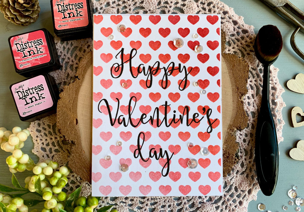 Handmade Valentine's day card with a heart background created with a stencil and red and pink Distress inks blended to create an ombre effect.