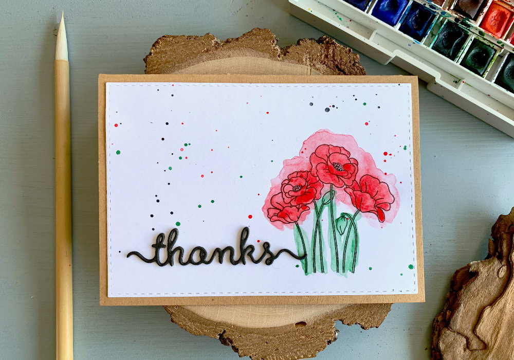 Handmade thank you card with stamped poppies on left side, coloured with red and green watercolours, doing the messy watercolour technique. And on the other side a greeting saying thanks, die-cut out of black card stock and adhered onto the panel.