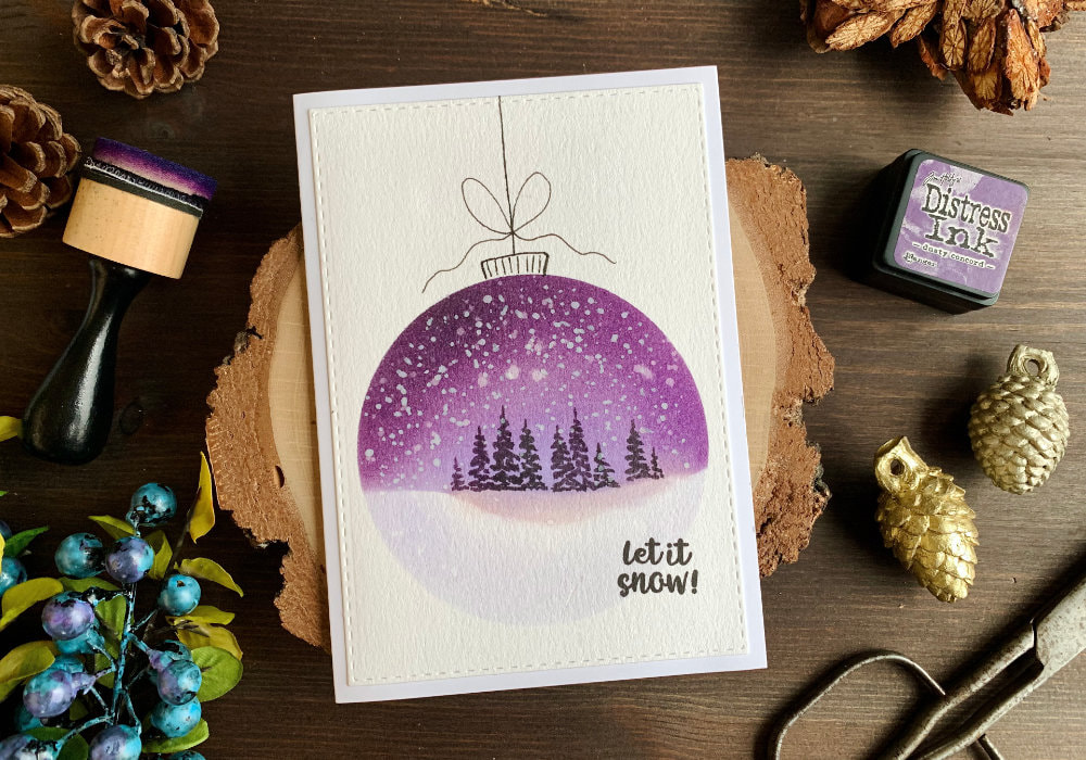 Handmade Christmas card with baubles created with Distress inks and a (DIY) circle stencil. One big bauble with landscape - a night sky and a snowy ground created with purple inks. Trees are painted with black ink and snow is created with white gouache.