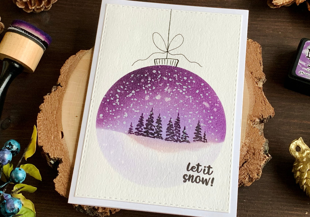 Handmade Christmas card with baubles created with Distress inks and a (DIY) circle stencil. One big bauble with landscape - a night sky and a snowy ground created with purple inks. Trees are painted with black ink and snow is created with white gouache.