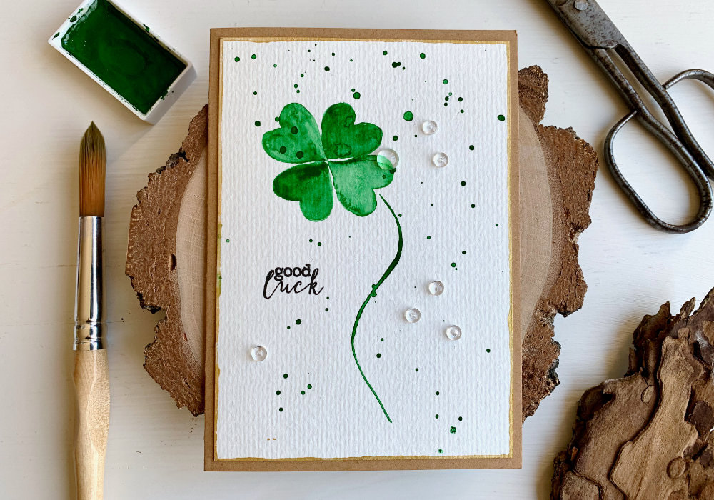 Handmade card for St. Patrick's day with a green watercolour lucky clover and a Good Luck greeting stamped in black.
