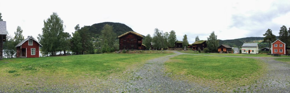 View of the Valdres Folk Open Air Museum in Norway. With old wooden houses in different sizes, some red, some brown.