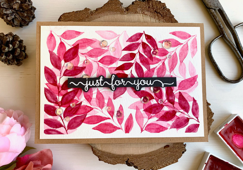 Handmade card with a leaf background painted with watercolours, layered on top of each other using three shades of pink and a greeting banner saying "just for you" stamped on a black card stock, heat embossed in white and adhered in the middle of the card.
