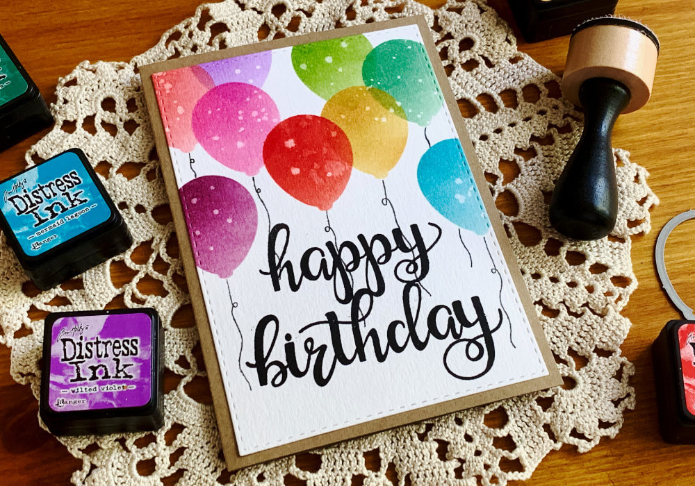 Handmade Birthday card with a big black Happy Birthday greeting and balloons in various colours above it.