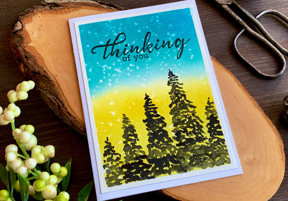 Handmade card with a blue and yellow background and silhouette of trees to support people in Ukraine.