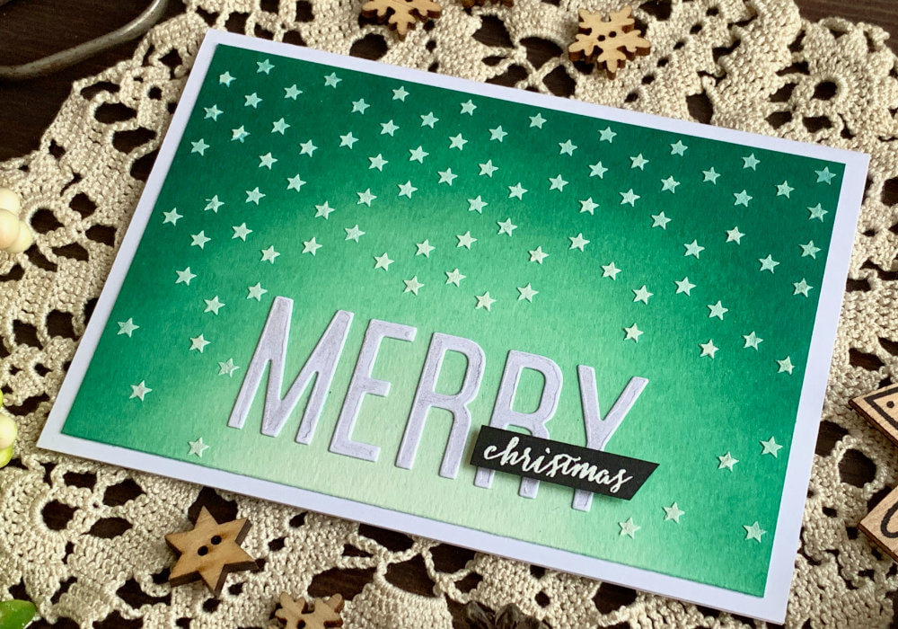Handmade Christmas card with a teal Distress ink background using the inks Pine Needles, Lucky Clover and Cracked Pistachio. Covered with stars made using a stencil and embossing paste.