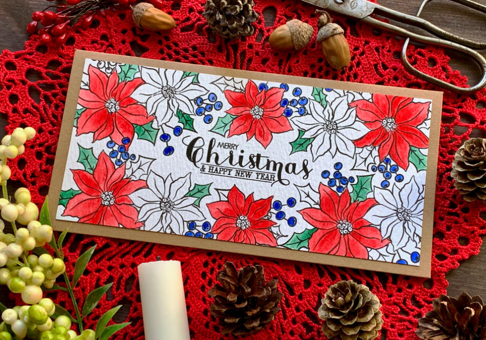 Handmade Christmas card with poinsettia flower  that are stamped along the edges of the card stock creating a frame. The stamp set used is the Holiday Bouquet stamp set by Avery Elle. Some of the flowers are coloured with watercolours some are black and white and the sentiment says Merry Christmas.