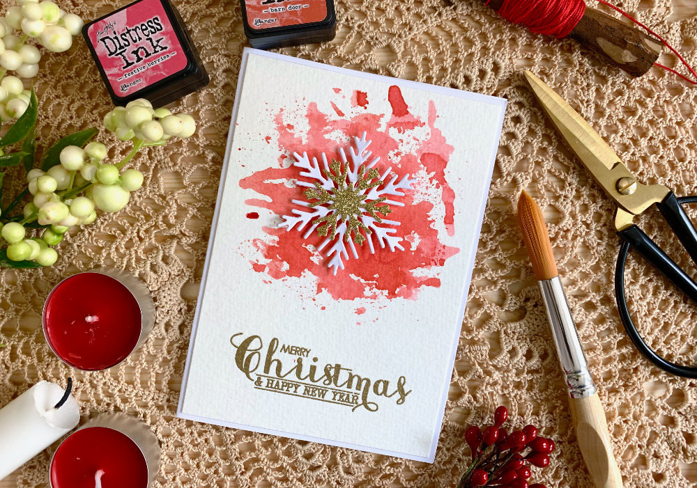 Handmade DIY Christmas card using a sparkly snowflake die cuts and creating a background using the Distress ink watercolour smooshing technique.