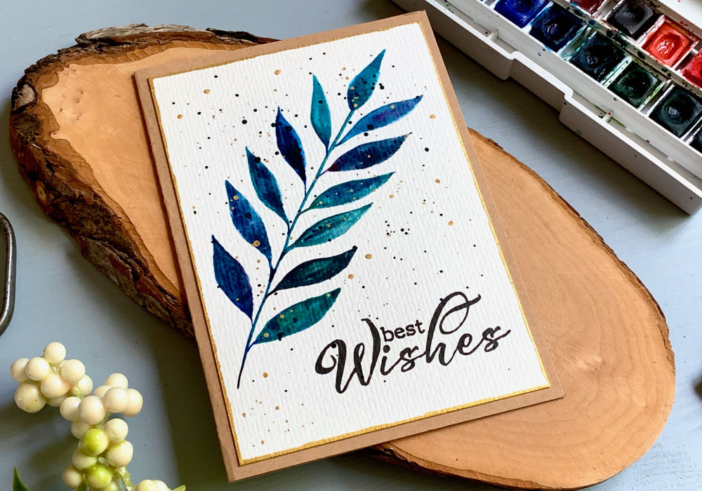 Simple handmade card with a brunch with leaves painted with watercolours in shades of blue and green and mixed with little bit of black and purple. And stamped greeting saying Best Wishes.