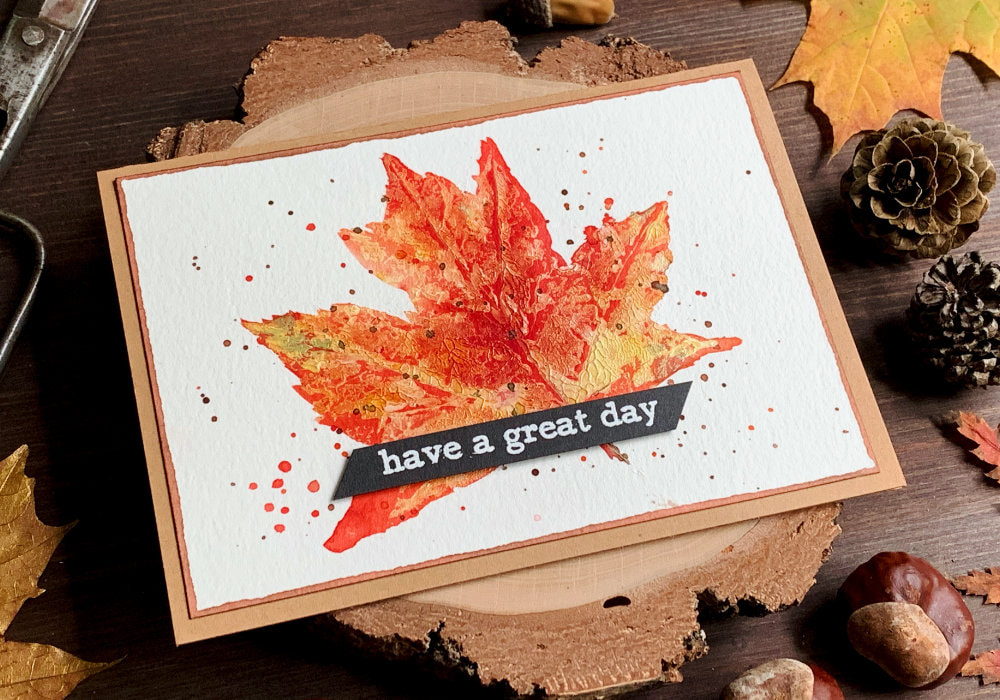 Handmade Birthday card with a stamped maple leaf using white acrylic paint and coloured white the Brusho watercolour powders using reds and oranges. The greeting 