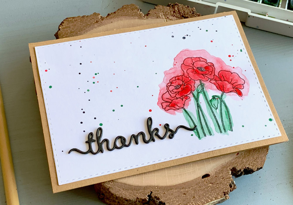 Handmade thank you card with stamped poppies on left side, coloured with red and green watercolours, doing the messy watercolour technique. And on the other side a greeting saying thanks, die-cut out of black card stock and adhered onto the panel.