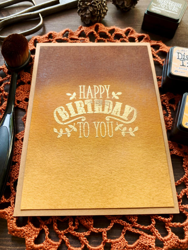 Happy Birthday handmade greeting card with an ink blended background using earthy colours - dark brown, orange and dark yellow. The greeting says Happy Birthday To You and is heat embossed in gold.