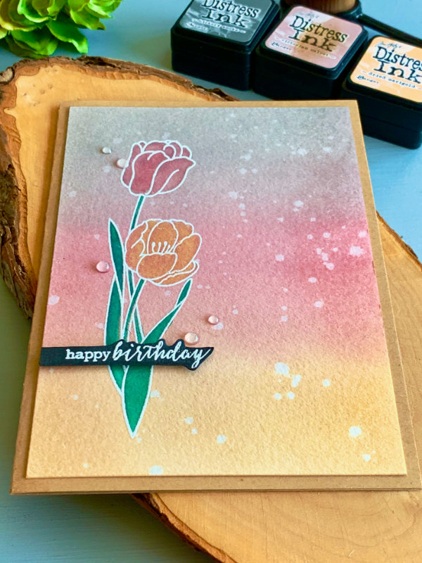 Handmade Birthday card with a background created with Distress inks in colours grey, pink and yellow and a stamped tulips heat embossed in white and watercoloured using the Distress inks - green, pink and yellow. 