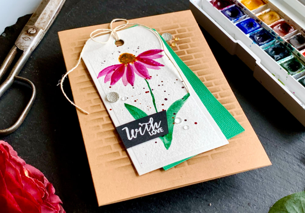 Handmade greeting card with a watercolour coneflower painted onto a tag adhered onto a craft card base with a brick background. The greeting says With Love.