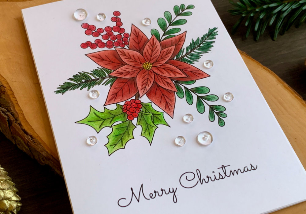 Handmade Christmas card with an image of poinsettia bouquet including a holly and berry and fir tree branches. The image is coloured with the Faber-Castell Polychromos colouring pencils using reds and greens.