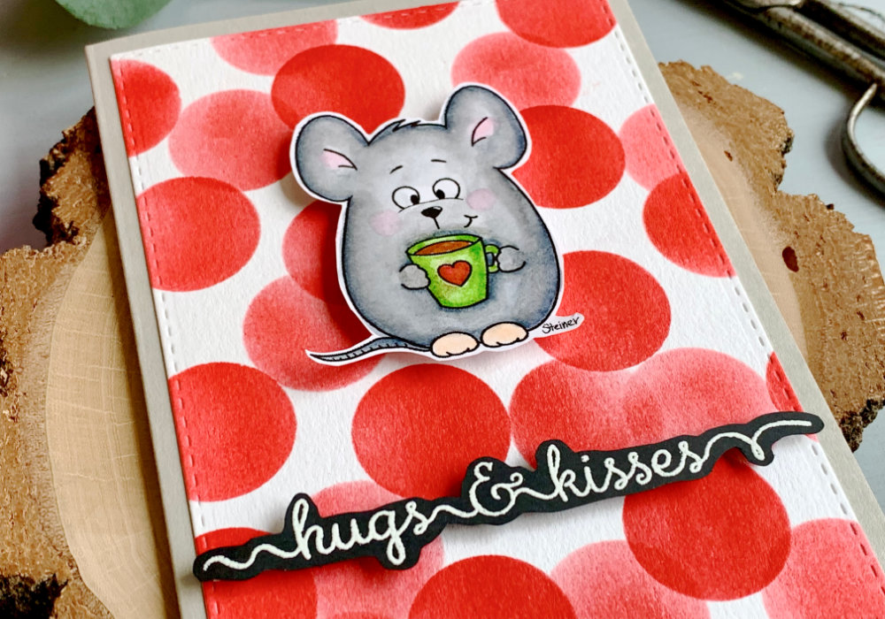 Handmade Valentine's day with a printed digital stamp of a mouse holding a cup of coffee. Coloured in grey with the Zig brush markers and adhered on a very vibrant background filled with red circles and greeting that say hugs & kisses.