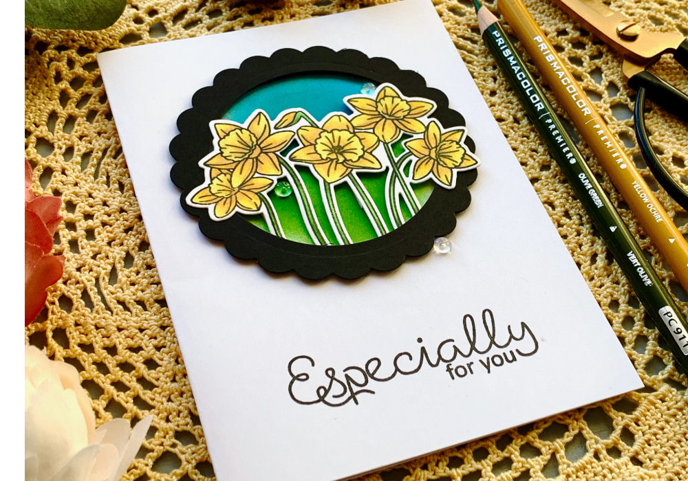 Simple spring card perfect for Mother's Day or Birthday filled with stamped and die-cut red daffodils using the Spring Daffodils or Spring Blooms stamp set from Clearly Besotted and coloured with the Prisma colouring pencils, paced into a stitched rectangular die-cut frame.