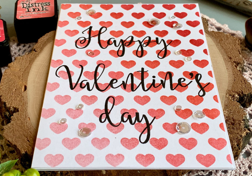 Handmade Valentine's day card with a heart background created with a stencil and red and pink Distress inks blended to create an ombre effect.