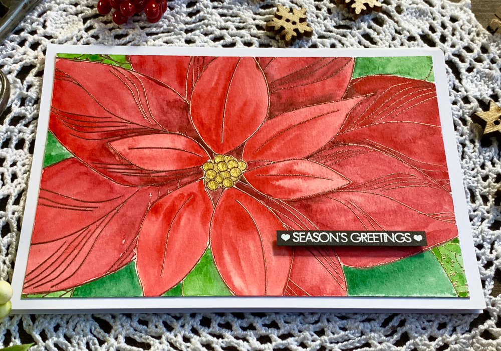 Handmade Christmas card with a big poinsettia, stamped and heat embossed and coloured in red with watercolours.