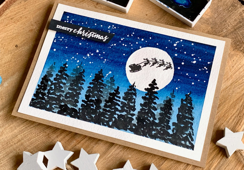 Simple  winter landscape Christmas card with a dark blue night sky and snow, moon with stamped silhouette of Santa's sleigh and reindeers and silhouettes of fir trees. 