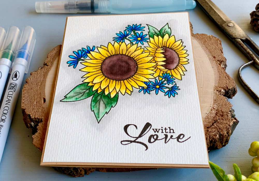 Handmade card for Mother's Day with a stamped sunflowers and coloured with water based markers. The sunflower is yellow with brown center and green leaves and tiny flowers coloured with blue markers. 