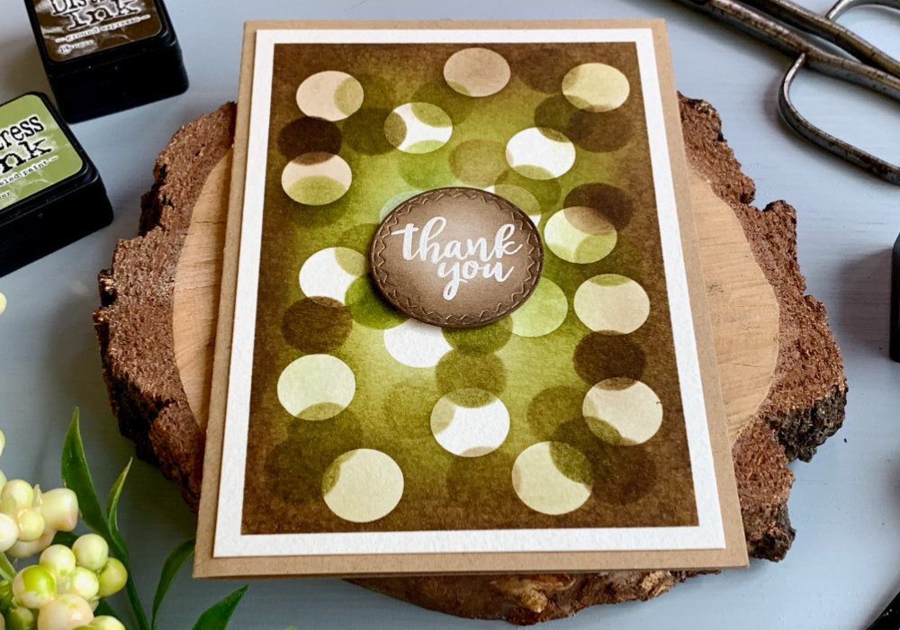 Thank you card with a bokeh effect over a brown-green background made with Distress inks. 
