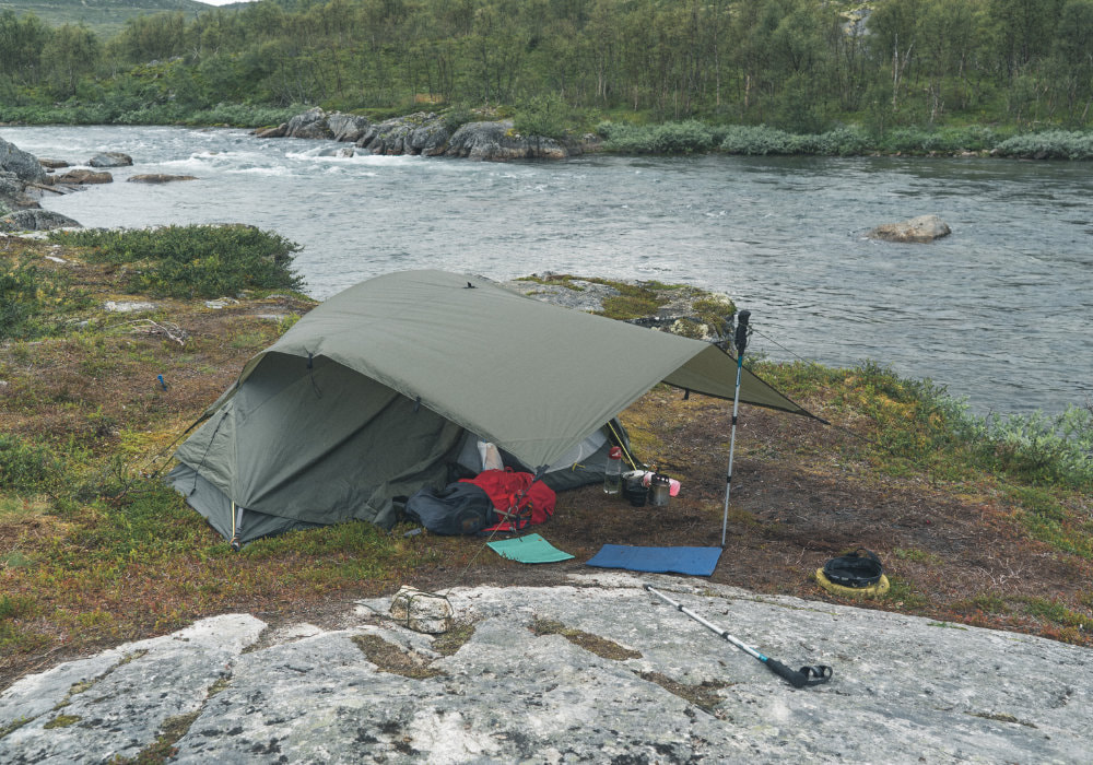 Tent camp set up in Hardangervidda Norway at a river during a gloomy and misty day.