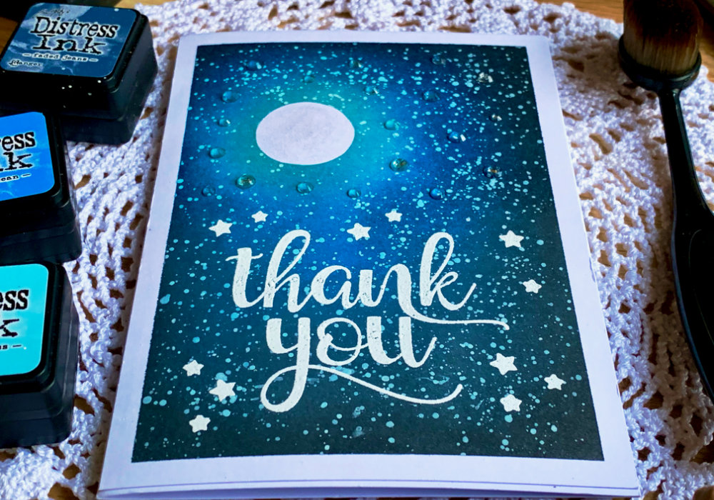 Handmade card with a night sky background with a moon and stars created with Distress inks and big Thank You greeting stamped and heat embossed in white. 