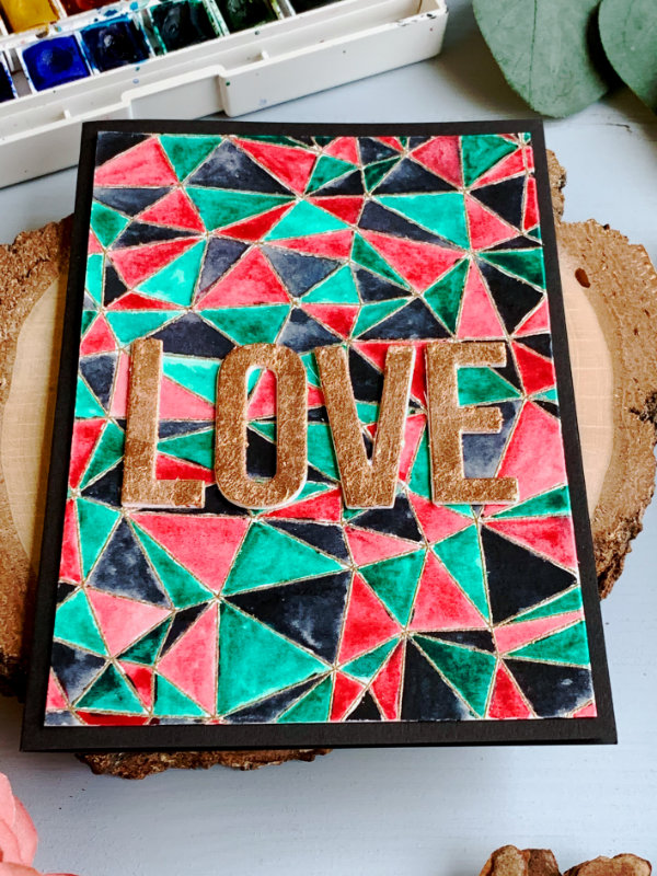 DIY Valentine's day card with stamped and heat embossed background with abstract pattern painted, in three colours - green, red and black and a greeting saying Love, die cut and embellished with gilding flakes in the colour of copper.