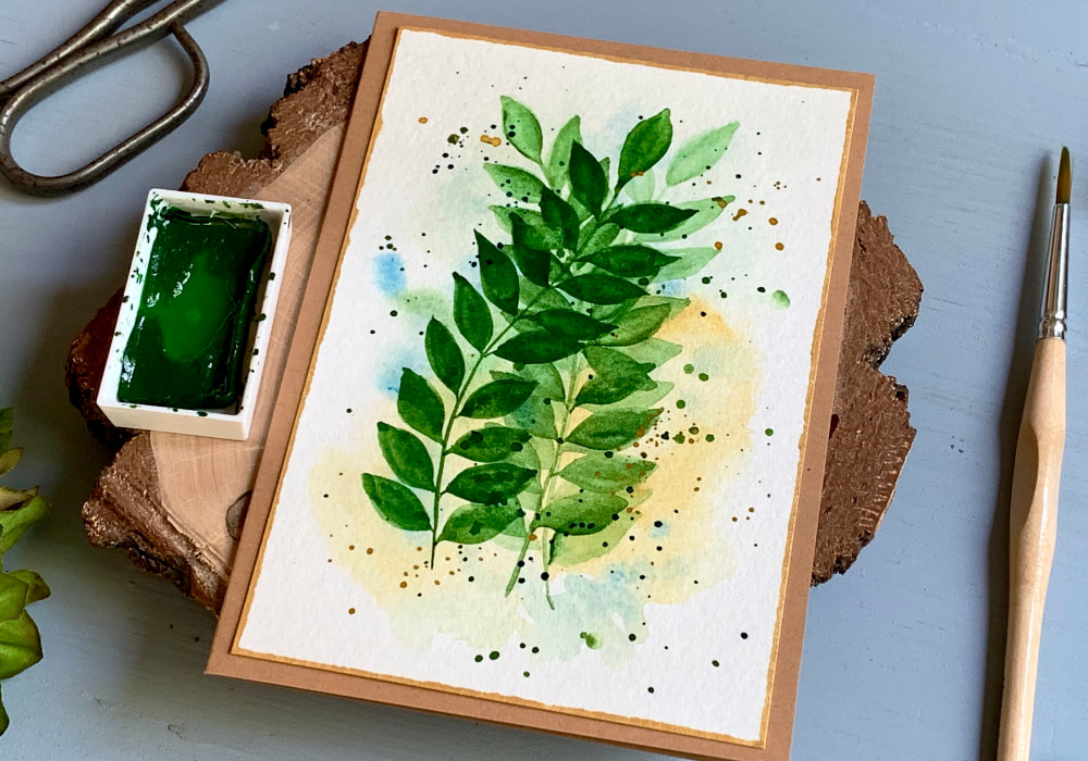 Handmade greeting card with overlapping leaves painted with watercolours in different shades of green.
