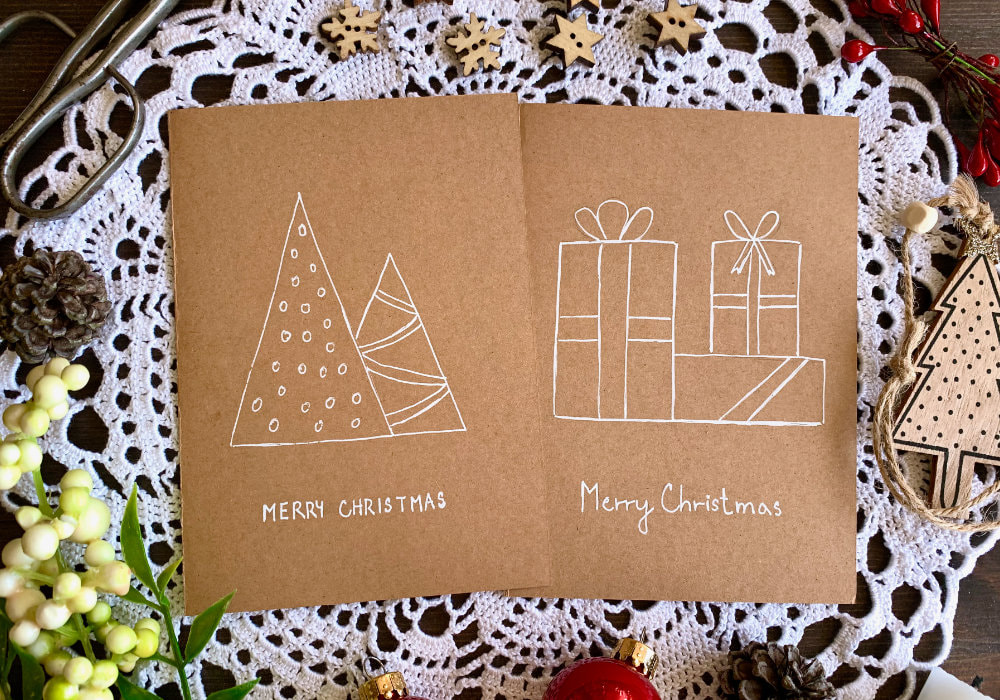Hand drawn Christmas cards, one with Christmas tree triangles and the other with three presents. Drawn on a craft card base with a gel pen.