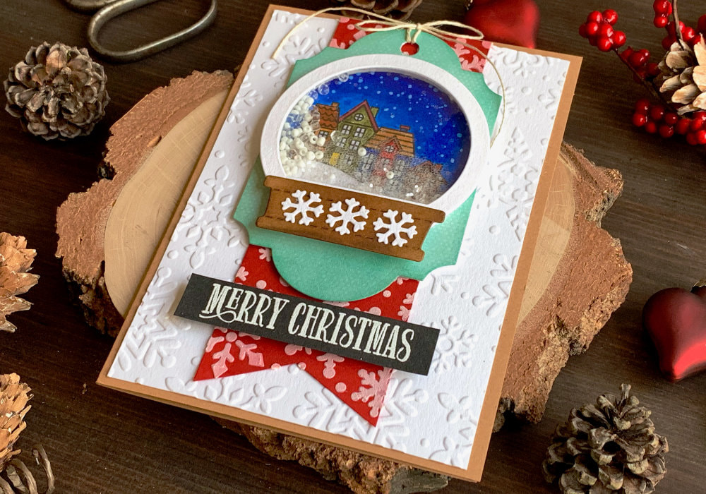 DIY Christmas card with a shaker snow globe filled with beads and background with stamped Christmas village at night. 
