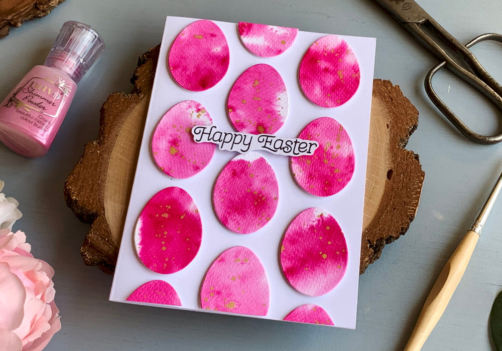 Handmade Easter greeting card with a backround filled with bright pink eggs. The background used for the eggs was created with a pink Nuvo Shimmer Powder. The greeting says Happy Easter.