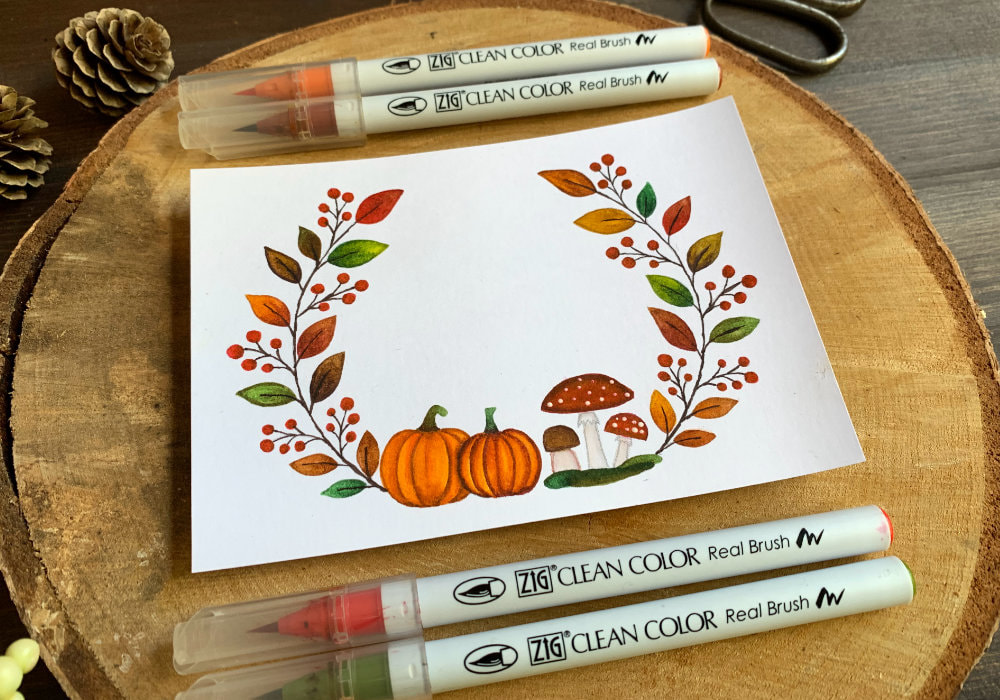 Handmade autumnal Birthday greeting card with a wreath with pumpkins and red mushrooms, leaves and berries on each side, coloured in autumnal colours using the Zig Brush Markers.