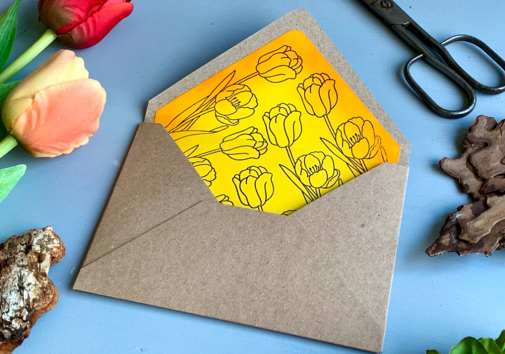 Handmade card with a yellow-orange tulip coloured with the Faber-Castell Polychromos pencils on a black cardstock, with a greeting heat embossed in white saying Just For You.