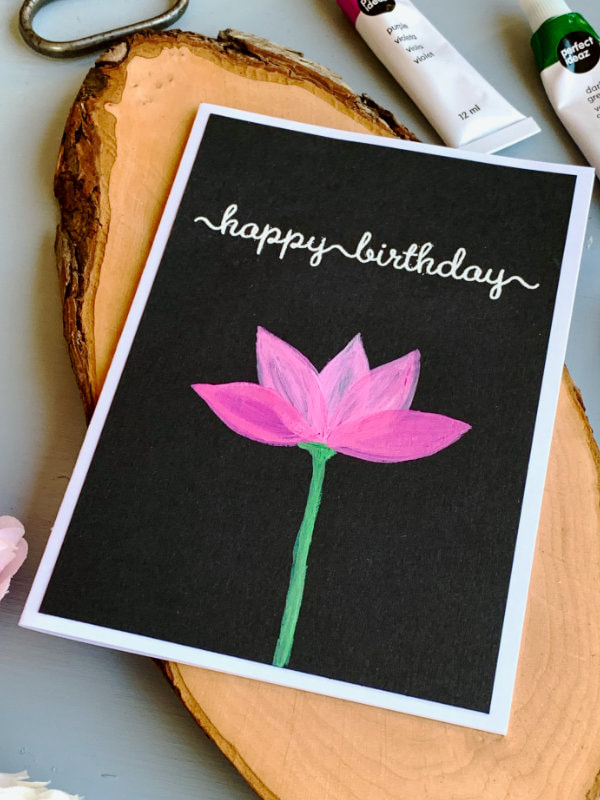 Simple Birthday card with a painted lotus flower using acrylic paints on a black card stock and a greeting heat embossed in white saying Happy Birthday. 