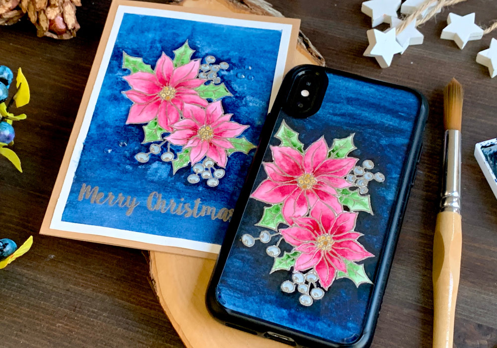 Handmade Christmas card & phone case insert with a stamped and heat embossed poinsettia, painted with pink watercolours and backround painted using very dark blue. The greeting says Merry Christmas and is also stamped and heat embossed using a metallic platinum embossing powder.