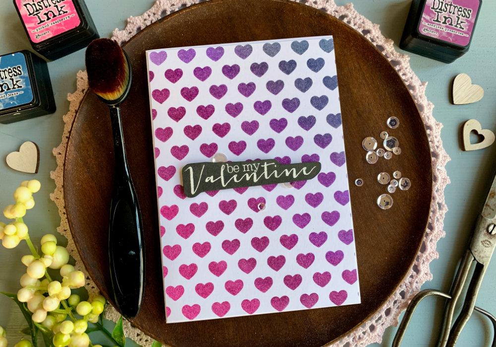 Simple handmade card for Valentine's day with a purple Distress ink bending combination using the inks Faded Jeans, Wilted Violet, Seedless Preserves and Picked Raspberry, blended over a stencil with hearts. 
