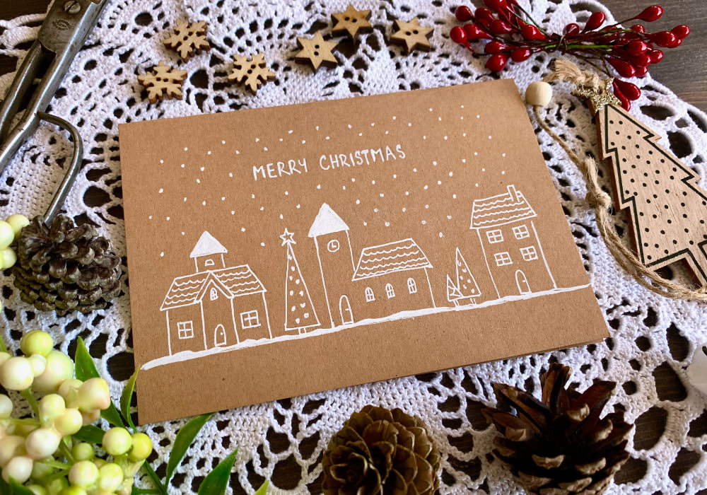 Hand drawn Christmas card with a Christmas village, drawn on a craft card base with a gel pen.